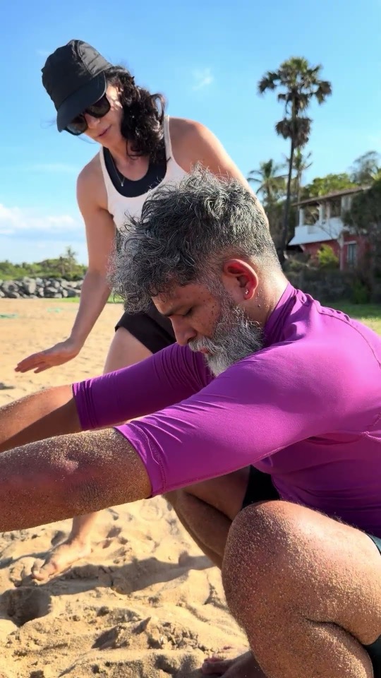 Rotem coaching a seated client through the squat setup on the beach